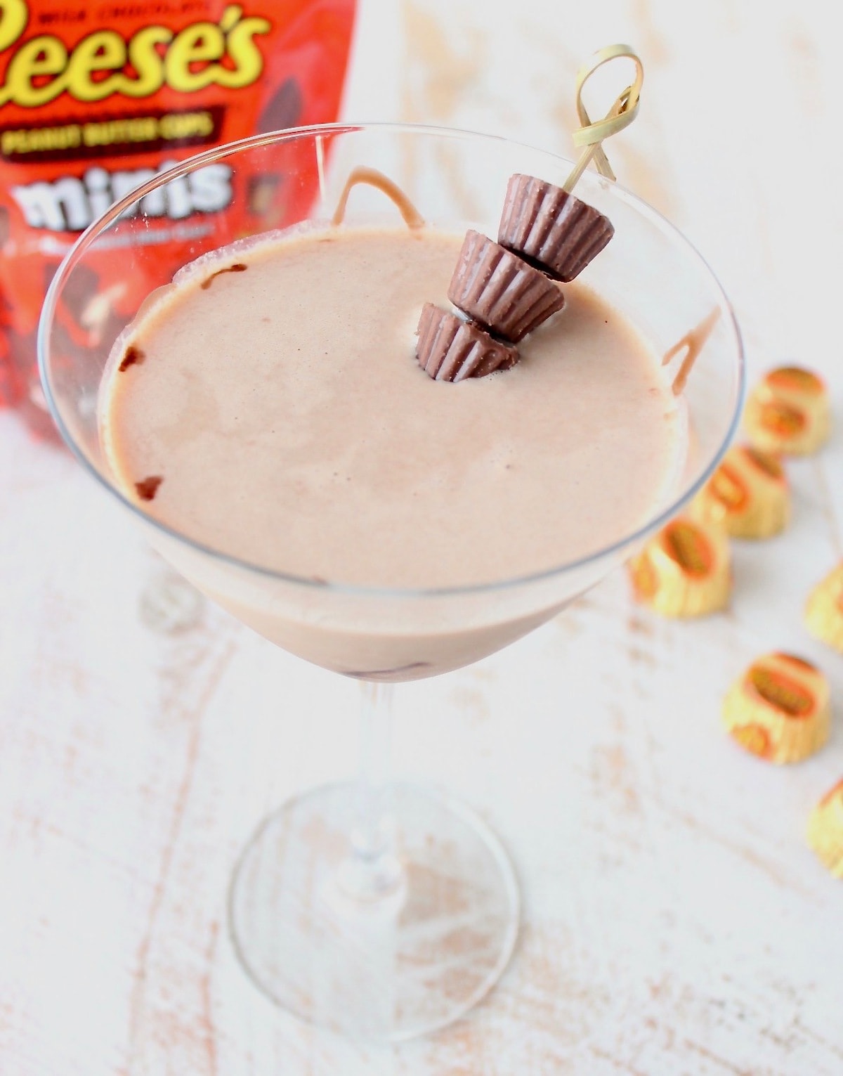 Reese's Martini in martini glass with skewer of mini reese's peanut butter cups and orange bag of reese's peanut butter cups