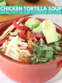 chicken tortilla soup in orange bowl, topped with diced avocado, shredded cheese and cilantro