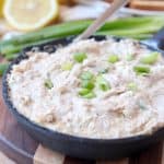 Creamy crab dip in cast iron skillet topped with diced green onions
