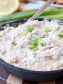 Creamy crab dip in cast iron skillet topped with diced green onions