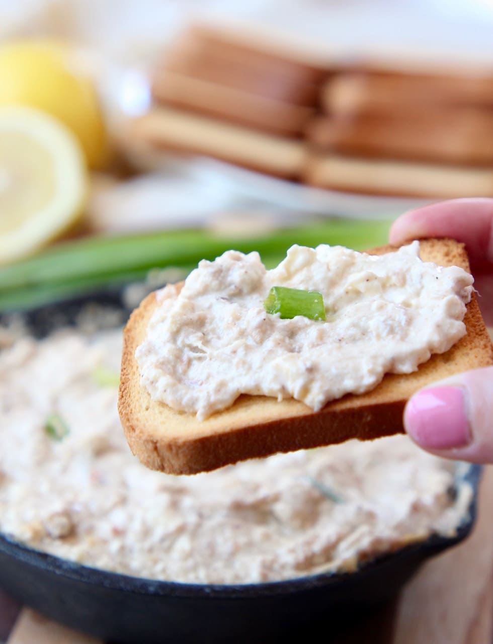 Hand holding brioche toast, topped with hot crab dip