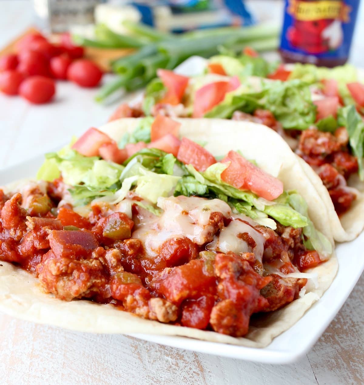 A flour tortilla topped with ground turkey, salsa, cheese, lettuce, and tomato.