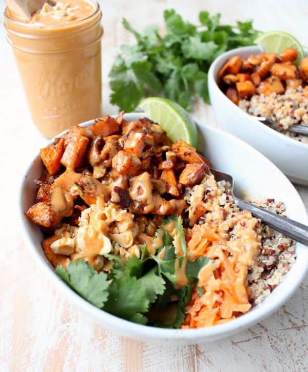 Roasted diced sweet potatoes in bowl with quinoa and thai peanut sauce