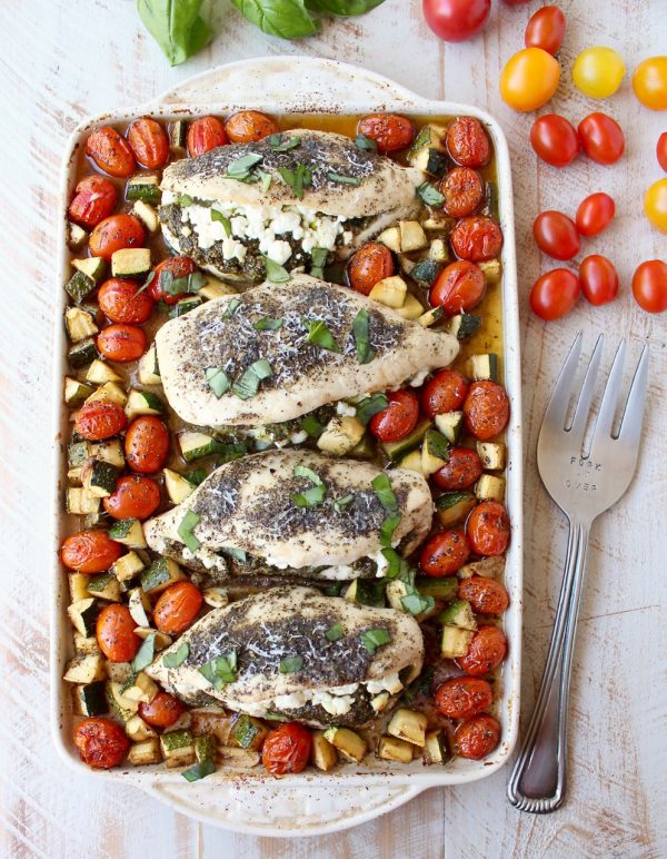 Sheet pan chicken is an easy, gluten free, one pan dish that takes under an hour to make. This recipe is stuffed with pesto and cheese, and served with zucchini and tomatoes!