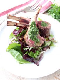 Rack of lamb is rubbed with herb butter, then roasted and topped with a mint chimichurri sauce in this elegant dinner recipe!