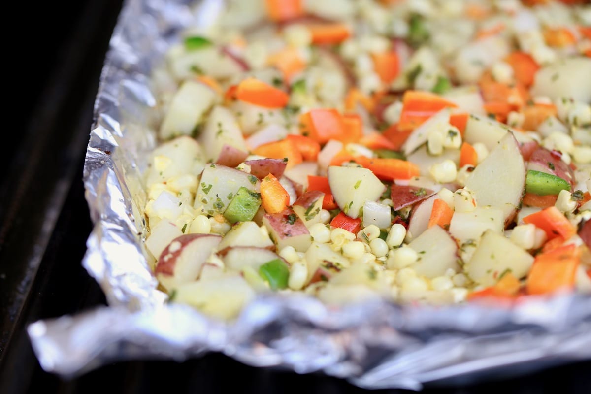 Potatoes, peppers, onions and garlic in a foil basket on the grill