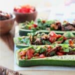 Mediterranean Tuna Salad with Roasted Red Peppers and Sun Dried Tomatoes Stuffed in Roasted Zucchini Boats on Wood Cutting Board