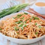 Pressure cooker chicken noodles with thai peanut sauce in bowl with diced green onions, shredded carrots and peanuts