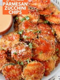crispy zucchini chips piled up on plate drizzled with buffalo sauce
