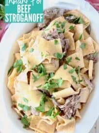 Overhead image of beef stroganoff with thick egg noodles in a white serving bowl