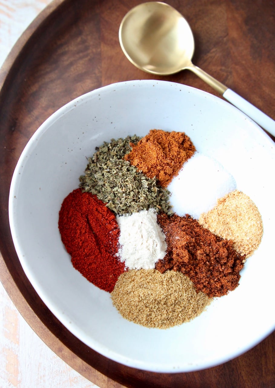 Fajita seasoning spices in white bowl on wood tray