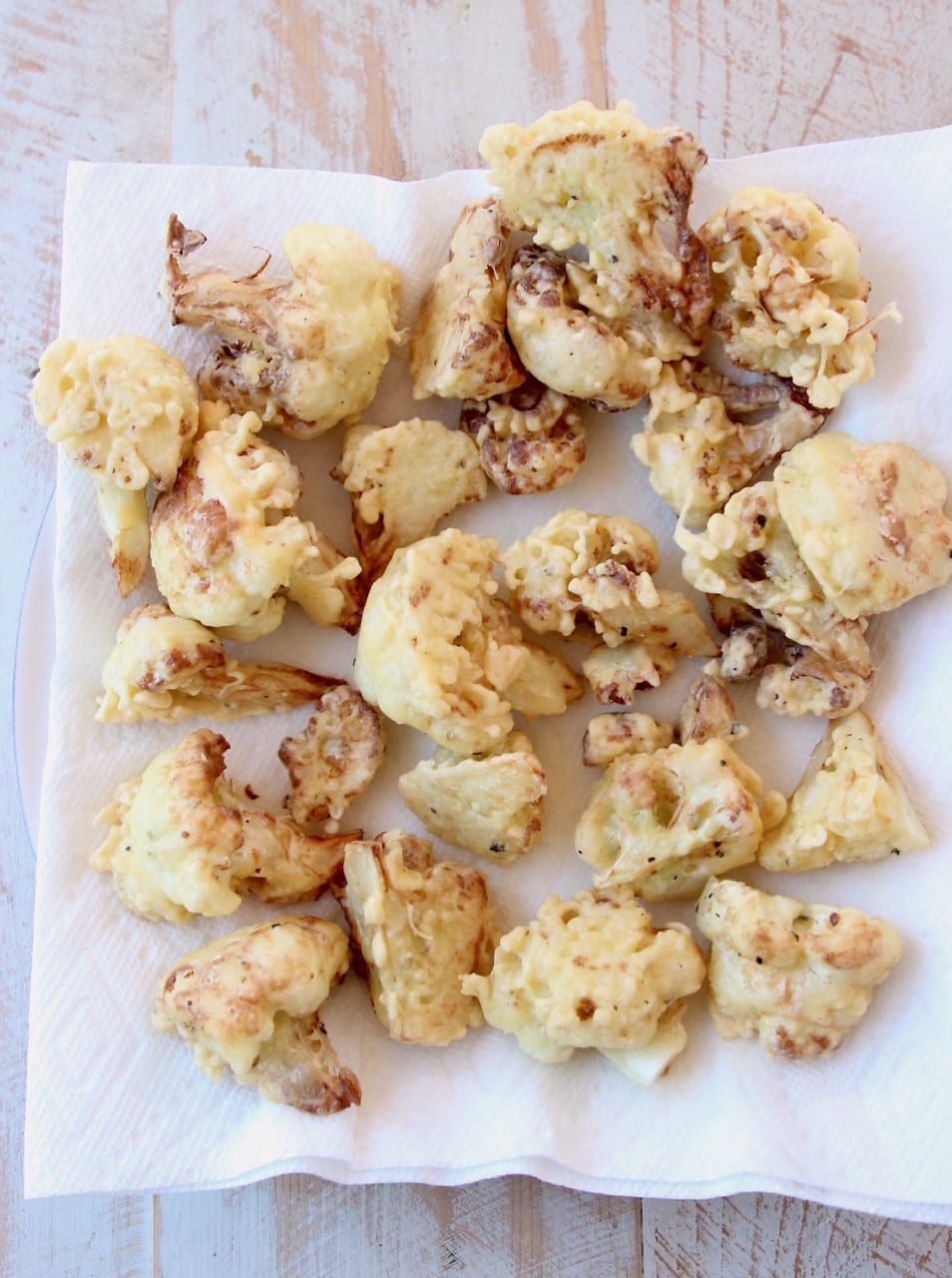 Fried cauliflower pieces on paper towel lined plate