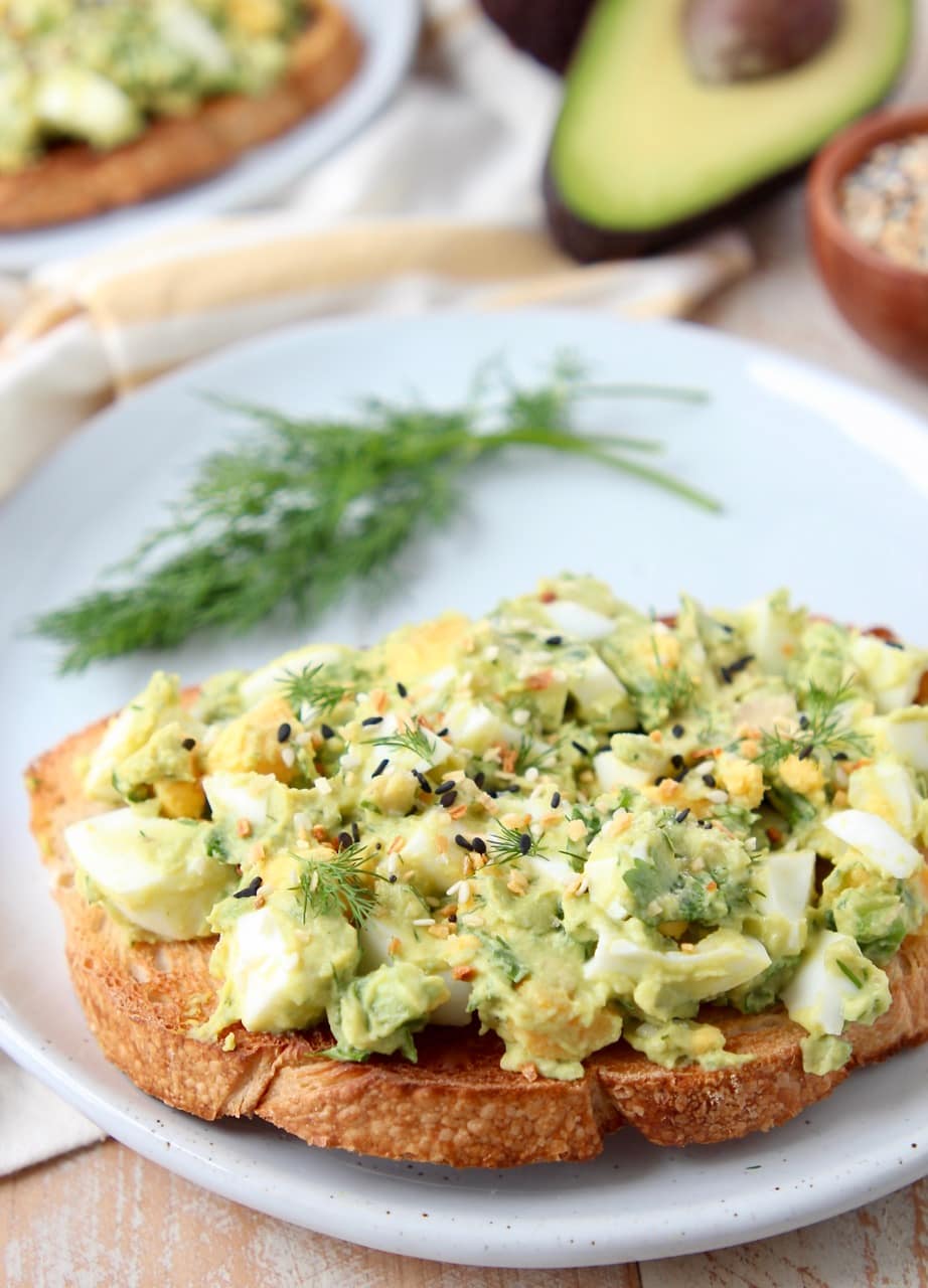 Avocado egg salad on toasted sourdough bread with fresh dill on white plate