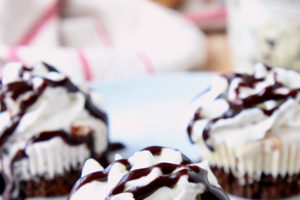 Ice cream cupcakes on plate topped with whipped cream and chocolate syrup