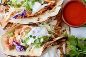 Buffalo chicken tacos with slaw and cilantro on plate