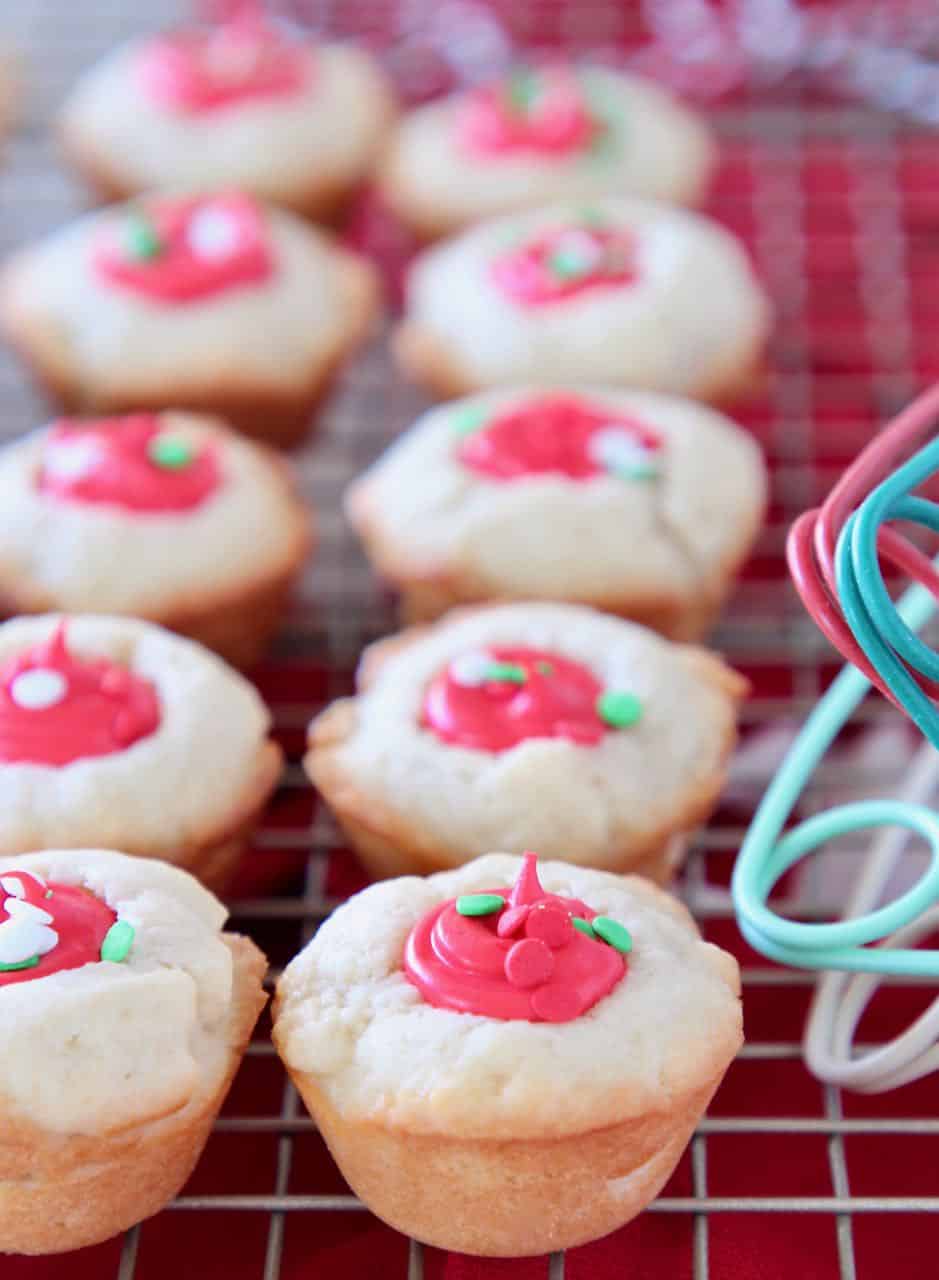 Sugar cookie cups with red frosting filling sitting on wire rack