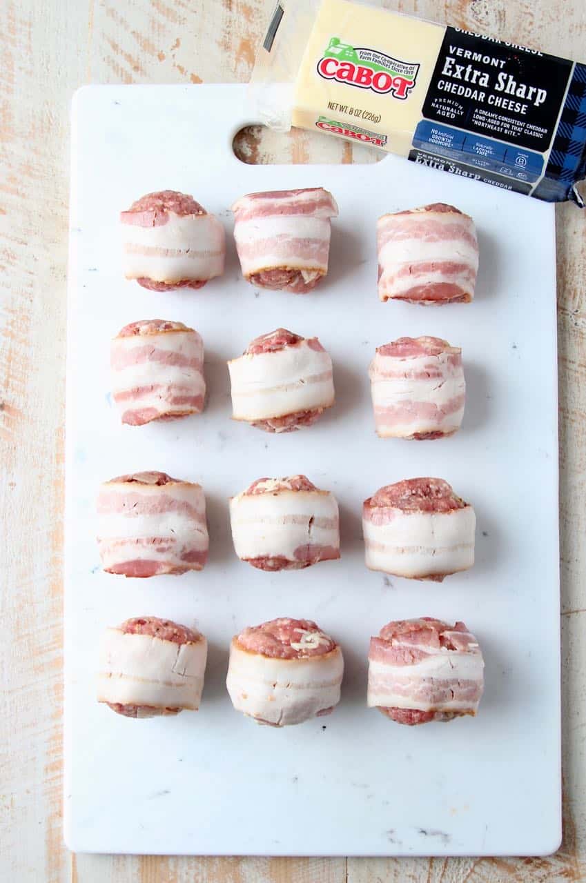 Raw bacon wrapped meatballs on white cutting board