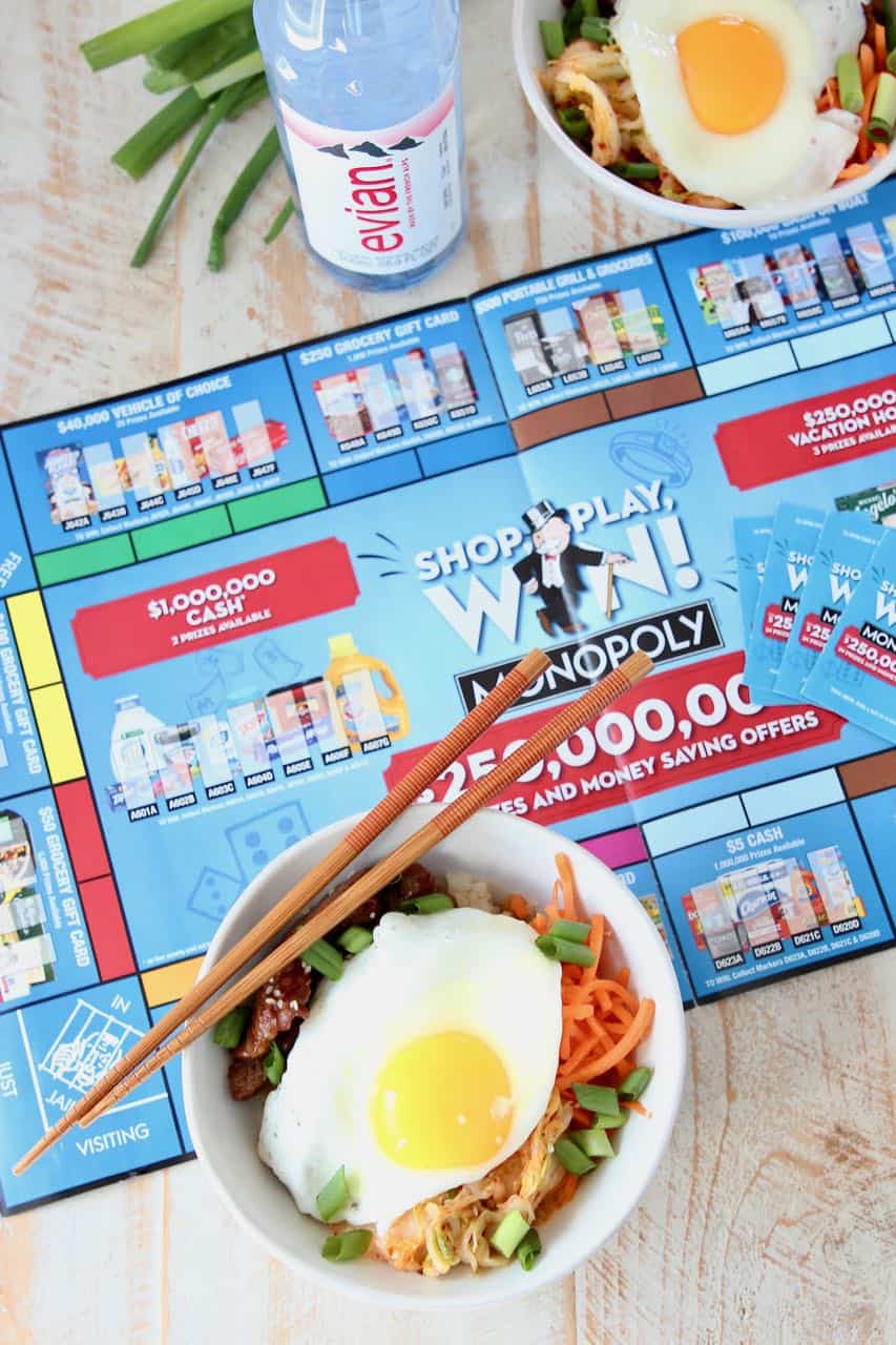 Korean BBQ rice bowls topped with fried egg sitting on Albertsons Monopoly board