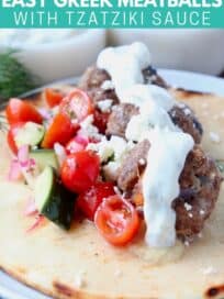 greek meatball gyro on plate topped with tzatziki sauce