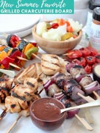 Grilled skewers on charcuterie platter with bowls of sauce