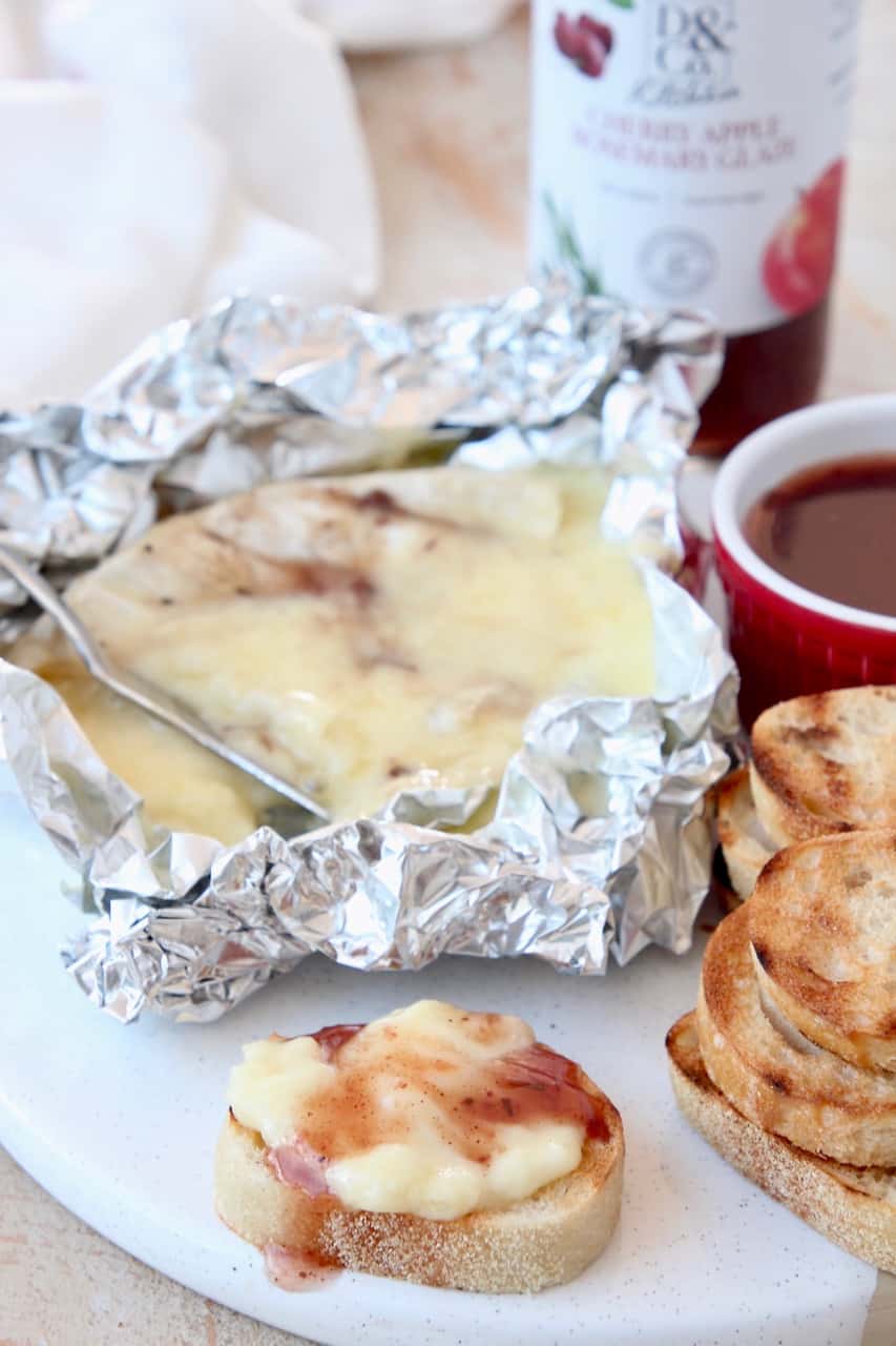 Melted grilled brie in piece of foil with baguette slices