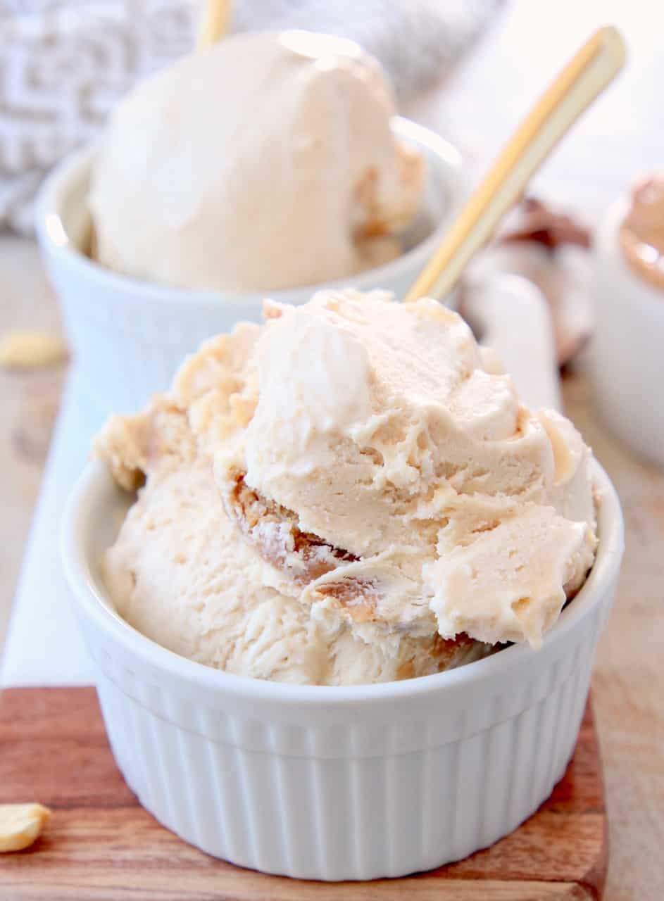 Scoops of peanut butter ice cream in bowls with gold spoons