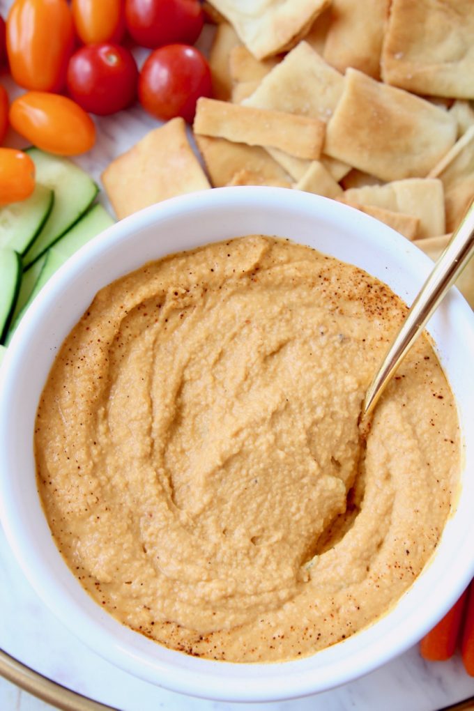 Spicy hummus in bowl with gold spoon