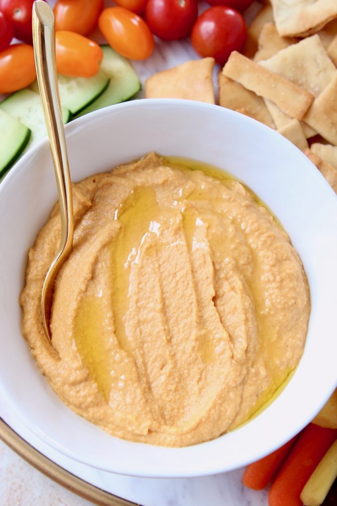 Spicy hummus in bowl with gold spoon