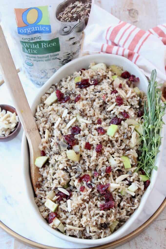cooked wild rice pilaf in serving dish with spoon and fresh herbs