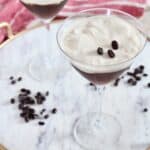 two espresso martinis on marble serving tray with coffee beans
