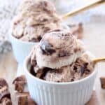 scoops of moose tracks ice cream in white bowls with gold spoons