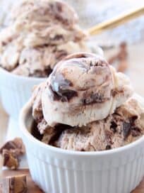 scoops of moose tracks ice cream in white bowls with gold spoons