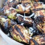 grilled brussels sprouts in bowl topped with grated parmesan cheese