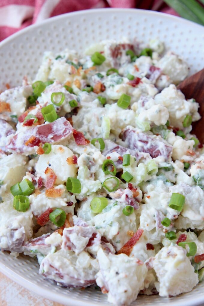potato salad topped with crumbled bacon and diced green onions in bowl