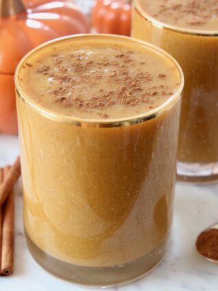 pumpkin smoothie in glass topped with ground cinnamon