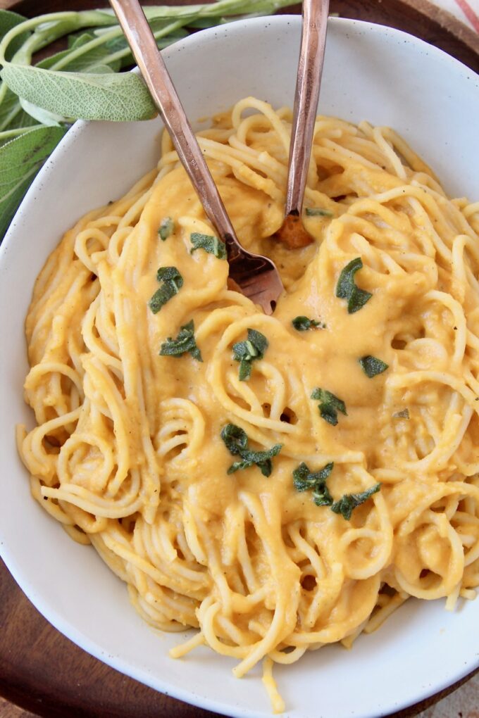 spaghetti noodles tossed with butternut squash sauce in bowl with two forks