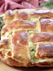 baked pot pie with weaved puff pastry crust on wood cutting board with fresh thyme