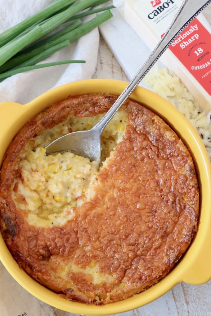 corn casserole in yellow baking dish with serving spoon