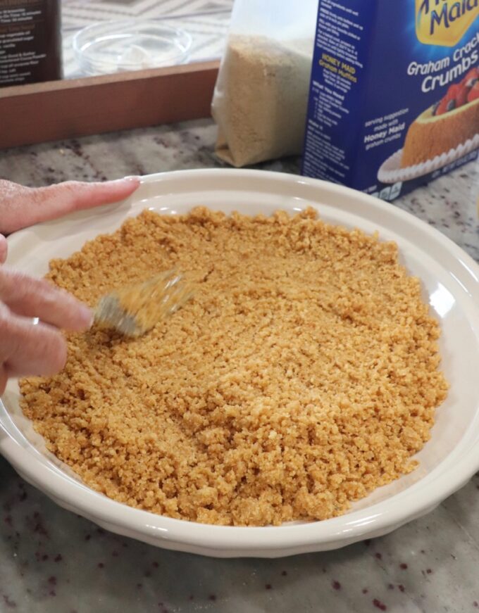 graham cracker crust being prepared in pie plate
