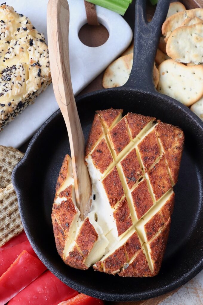 wooden knife in block of smoked cream cheese in cast iron skillet