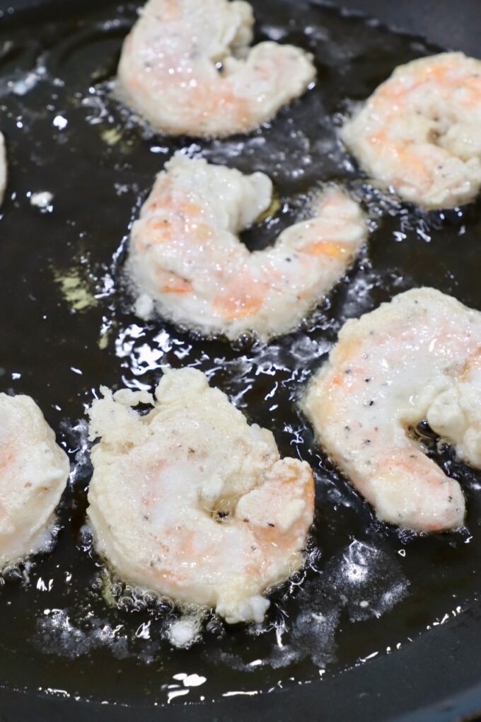 battered shrimp cooking in oil in skillet