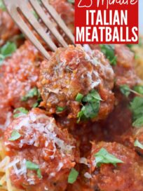 cooked Italian meatball in bowl with marinara sauce, spaghetti and fork