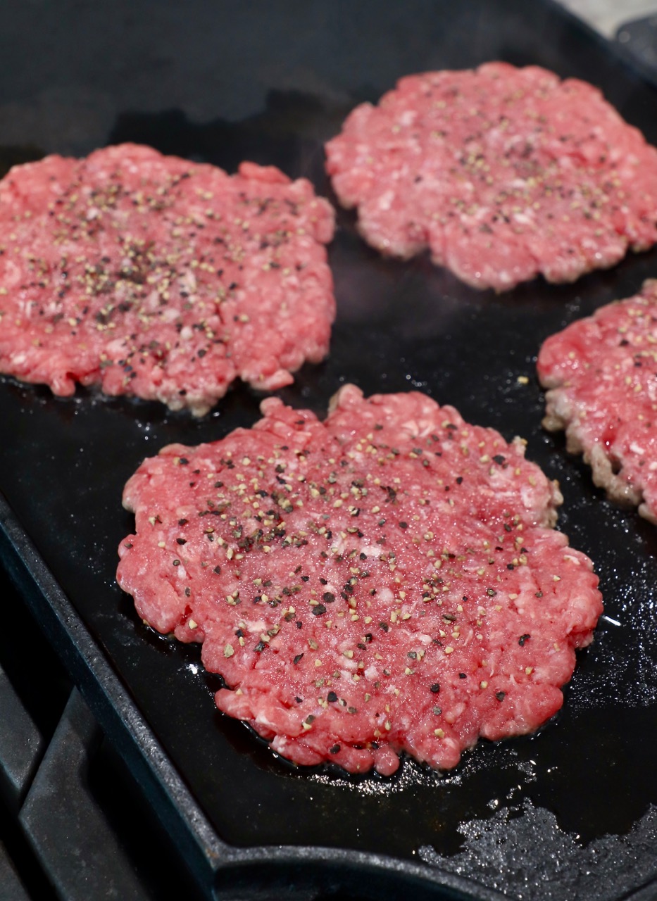 seasoned burger patties on cast iron griddle
