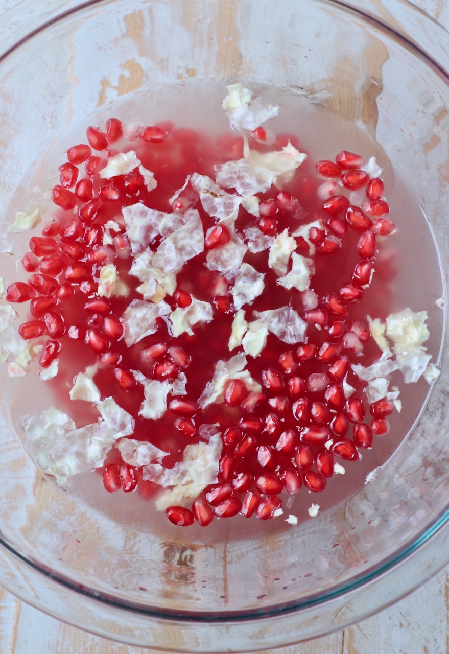 pomegranate seeds in glass bowl of water