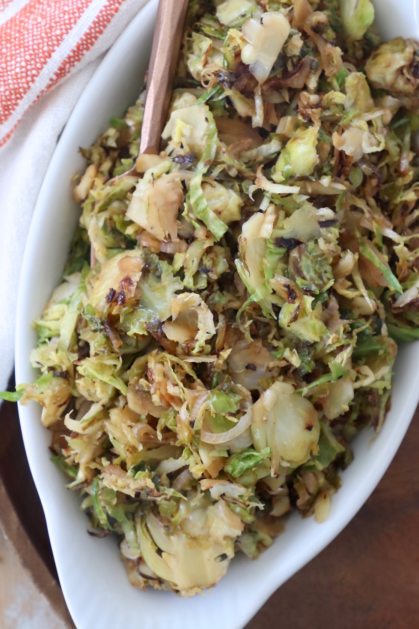 cooked shredded brussels sprouts in white serving dish