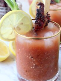 bloody mary in glass with lemon wedge and candied bacon