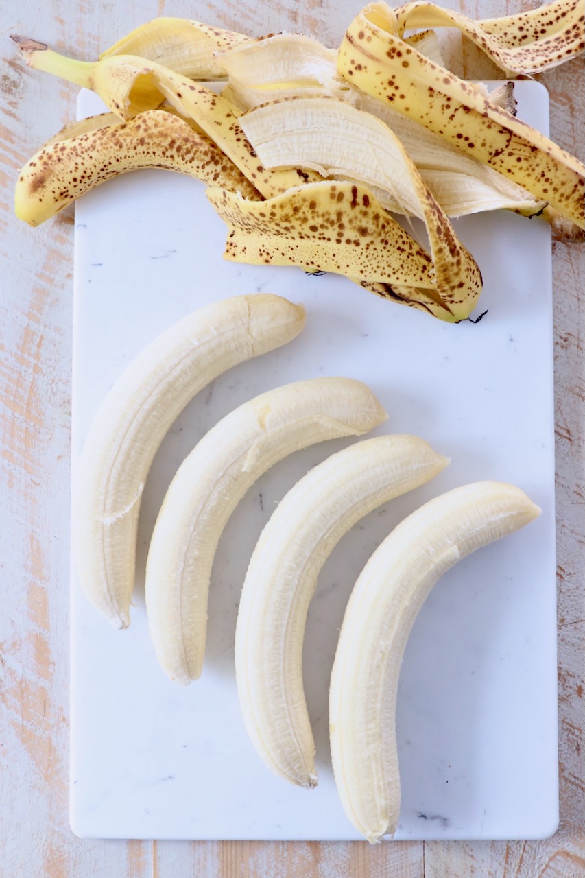 bananas with the peels removed on cutting board