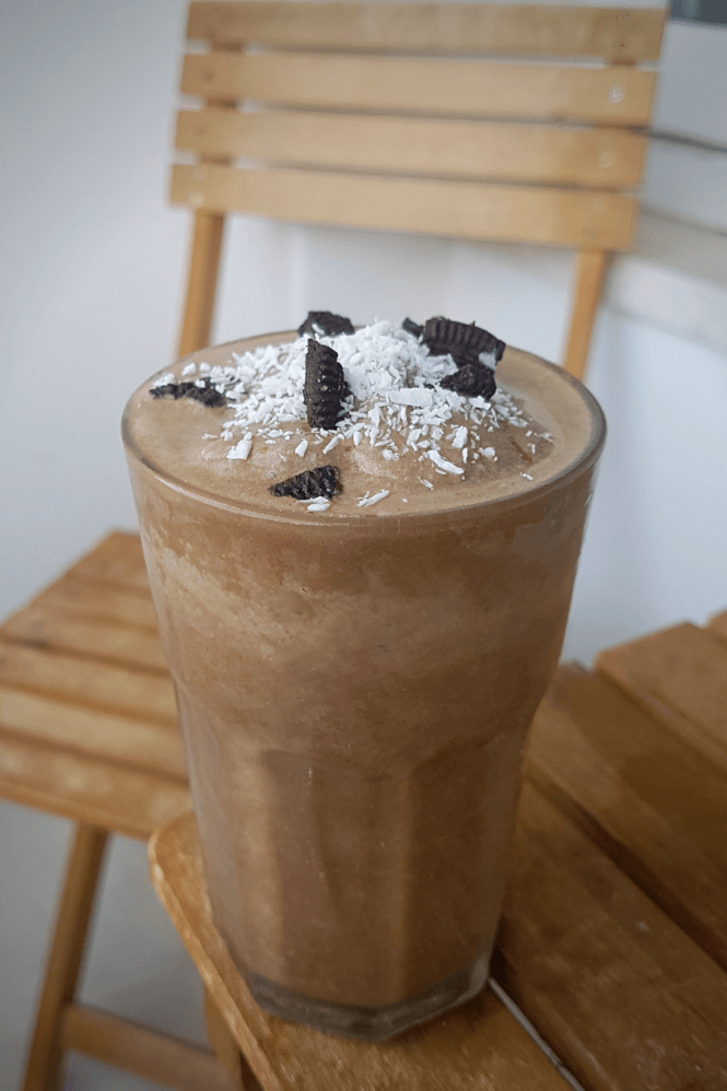 Vegan oreo coffee frappe in a glass with crushed oreo cookie and shredded coconut topping