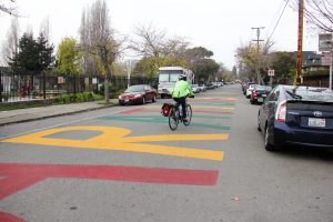 A bicyclist rides down a street in South Berkeley painted the words "Reparations Now."