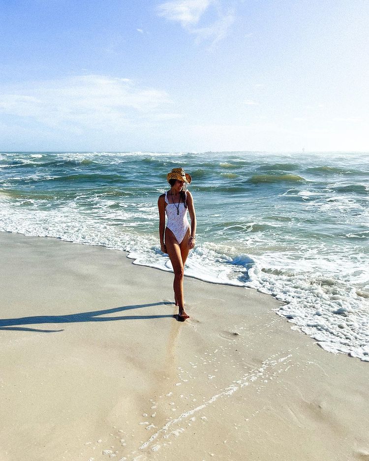 Girl walking at the sandy beach while waves are touching her feet. 